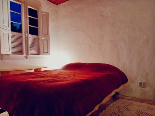 a bedroom with a red bed in a room with a window at Casa da Áfrika - Suíte Jasmin in Itanhandu