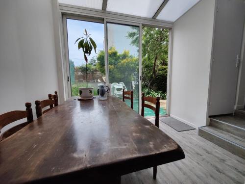 une salle à manger avec une table en bois et une grande fenêtre dans l'établissement Maison coeur de ville, à Montpellier