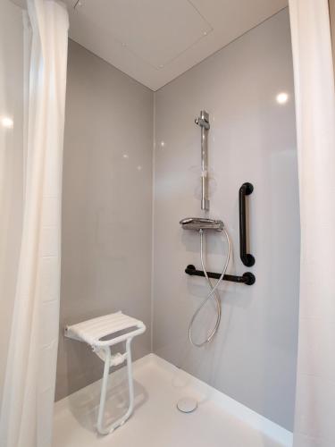 La salle de bains blanche est pourvue d'un tabouret et d'une douche. dans l'établissement Auberge Le LEO de FOIX, à Foix