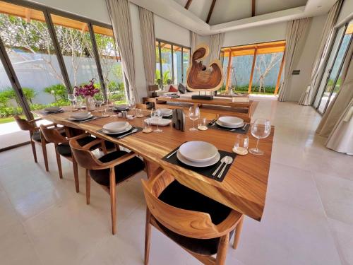 a dining room with a large wooden table and chairs at New luxury villa with maid Anchan Tropicana in Bang Tao Beach