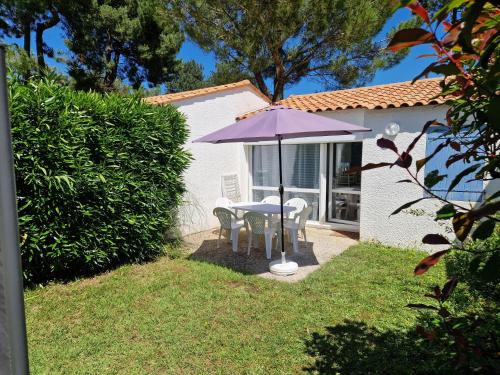 - une table et des chaises sous un parasol dans la cour dans l'établissement Charmante petite maison pour 4 personnes CDC FR90C10G, à Dolus-d'Oléron