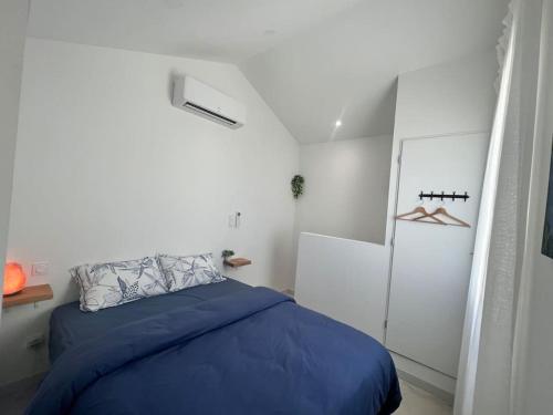 une chambre avec un lit bleu dans une pièce blanche dans l'établissement 9 écluses Canal du midi-Maison T3 belle vue avec Piscine, à Béziers