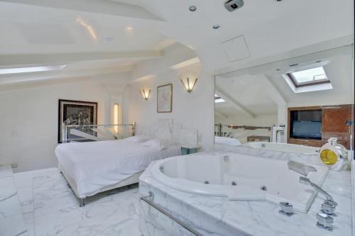 - une grande salle de bains blanche pourvue d'une baignoire et d'un lit dans l'établissement Louvre Terrace Apartment, à Paris