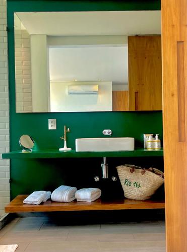 a green bathroom with a sink and a mirror at Pousada Rio144 in Rio de Janeiro