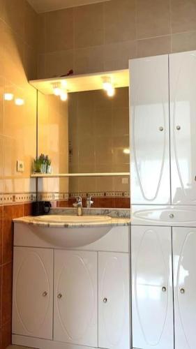 une salle de bain blanche avec un lavabo et un miroir dans l'établissement Appartement parisien et familial de 90m2, à Paris