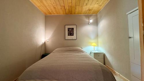 une chambre avec un lit avec un plafond en bois dans l'établissement Appt résidence 1650 ski aux pieds, à Courchevel