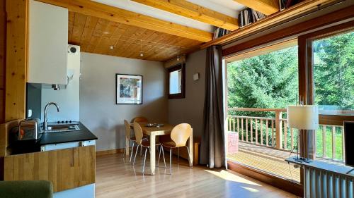 une cuisine et une salle à manger avec une table et une grande fenêtre dans l'établissement Appt résidence 1650 ski aux pieds, à Courchevel