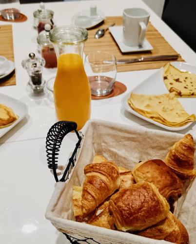 - une table avec un panier de pain et une bouteille de jus d'orange dans l'établissement LE JARDIN DE LA PICHONNERIE Chambres d'hôtes, à Thésée