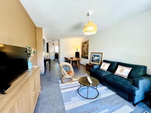 un salon avec un canapé et une télévision dans l'établissement La parenthèse - jardin privatif, à La Rochelle