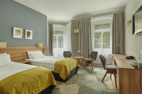 a hotel room with two beds and a desk at Impresja Art Resort in Duszniki Zdrój