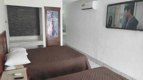 a room with two beds and a tv on the wall at Hotel Estrella in Matamoros