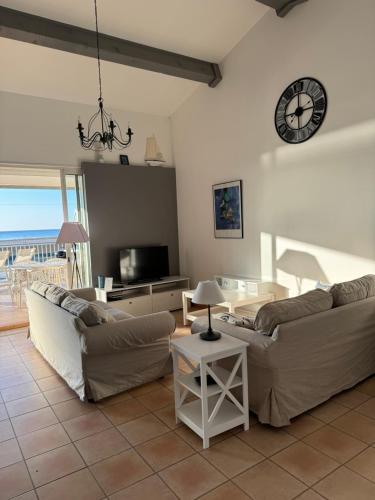 un salon avec deux canapés et une horloge au mur dans l'établissement Le Grand Large de Marie et Jean, à Gruissan