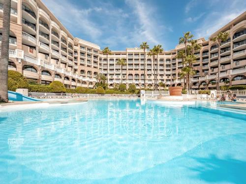 a large swimming pool in front of a large building at ON VACAY - Votre havre de paix à 100 m des plages in Cannes