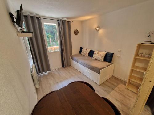 Cette petite chambre comprend un canapé et une fenêtre. dans l'établissement Studio cosy 4 pers avec balcon exposé Est, au pied des pistes - FR-1-265-238, à Valfréjus