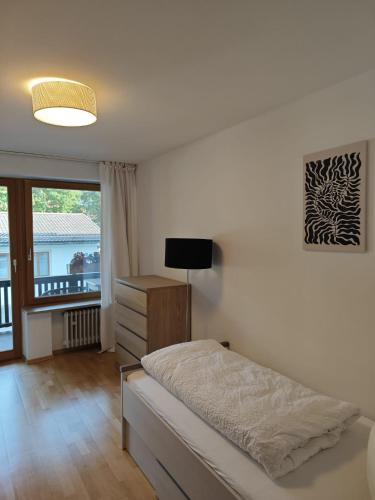 a bedroom with a bed and a television and a window at Hotel garni Königslinde - Wandern, Radeln, Skifahren & Genießen in Bayrischzell