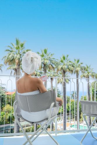 a woman sitting in a chair looking at the palm trees at So' Lifestyle Hotel Sorrento in Sorrento