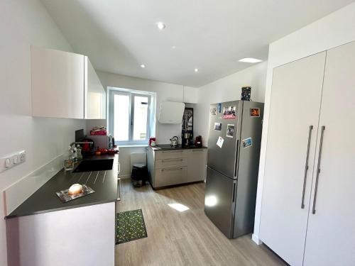 une cuisine avec un réfrigérateur en acier inoxydable et des armoires blanches dans l'établissement Bienvenue Chez Bob dans le centre-ville de Vivonne, à Vivonne