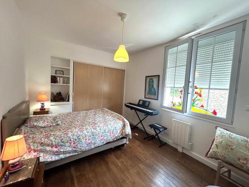 une chambre avec un lit et un bureau et deux fenêtres dans l'établissement Bienvenue Chez Bob dans le centre-ville de Vivonne, à Vivonne