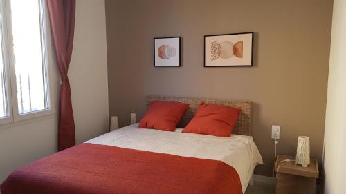 une chambre avec un lit avec des oreillers rouges et une fenêtre dans l'établissement Coquette maison canetoise, à Canet