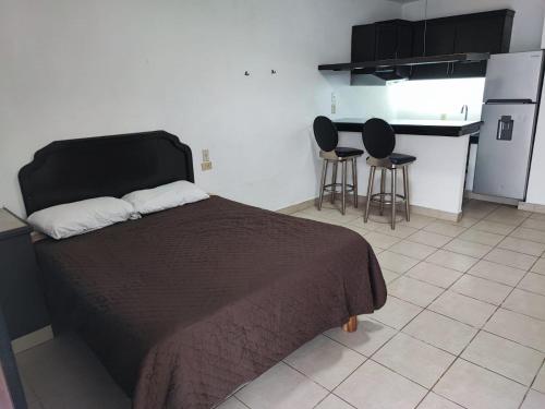 a bedroom with a bed and two chairs and a kitchen at Hotel Estrella in Matamoros