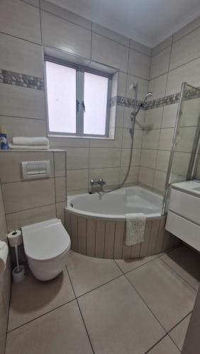 a bathroom with a tub and a toilet and a sink at Admirals Lodge Guest House and Brightways self catering apartments in Port Elizabeth