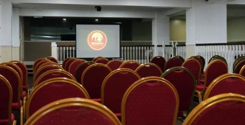 a lecture hall with red chairs and a screen at The Grand Burstin Hotel in Folkestone