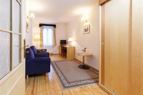 a living room with a blue couch and a table at Hotel Maltezský Kříž in Karlovy Vary