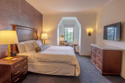 a bedroom with a large bed with a dresser and a desk at Morris Inn at Notre Dame in South Bend