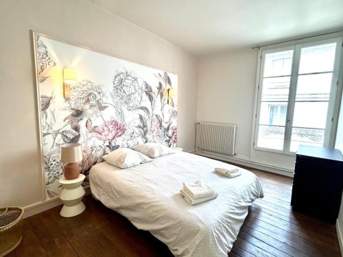 Un dormitorio con una cama blanca con un mural en la pared. en La Lorraine : cosy en centre ville, en Poitiers