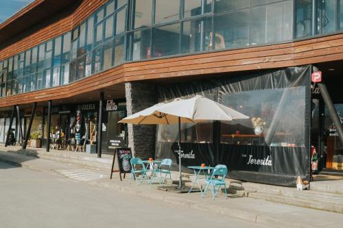 a table and chairs and an umbrella in front of a building at Hotel Terrazas del Lago in Puerto Varas