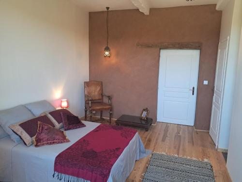 a bedroom with a bed and a chair and a door at Aux roses de Cèdres in Salvagnac