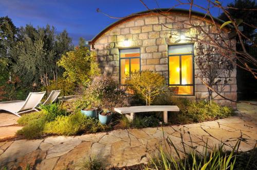 a stone house with a bench in front of it at טורקיז - בריכה פרטית in Had Nes