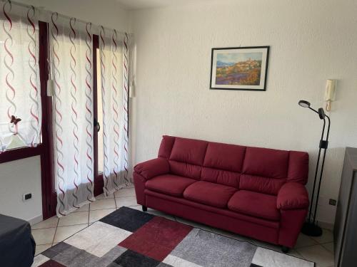 a red couch in a living room with two windows at Il Lago a Luino in Luino