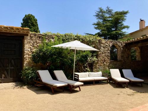 a group of chairs and an umbrella on a patio at Els Racons del Fort Castle hosting up to 18 people in Capmany