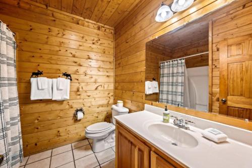 a bathroom with a sink and a toilet and a mirror at Misty Mountain Game Room and Hot Tub in Pigeon Forge