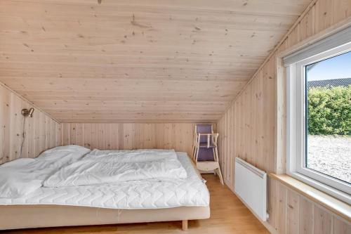 a bed in a wooden room with a window at 4 bedrooms and a beautiful view in Vinderup