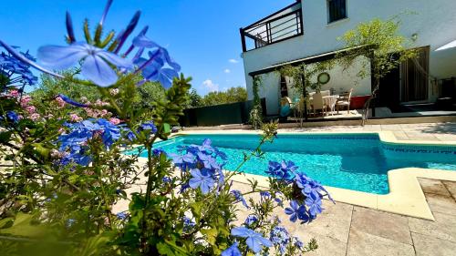 - une piscine en face d'une maison ornée de fleurs bleues dans l'établissement Loft sauna balnéothérapie, à Beaucaire