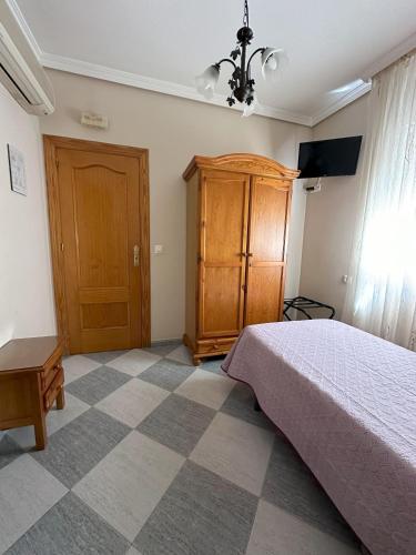 a bedroom with a bed and a wooden cabinet at Hostal Avenida in Tabernas