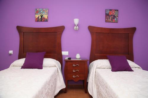 two beds in a room with purple walls at Hostal Avenida in Tabernas