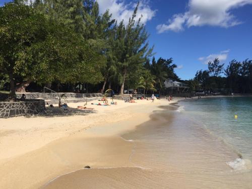 a beach with people laying on the sand and water at Appartement - A 300m de la mer in Pereybere