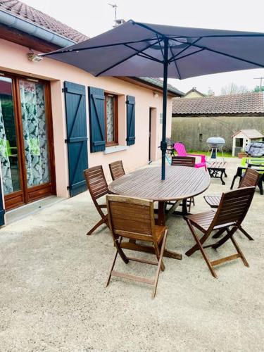 une table et des chaises avec un parasol sur une terrasse dans l'établissement La P'tite Ambrièroise, à Ambrières