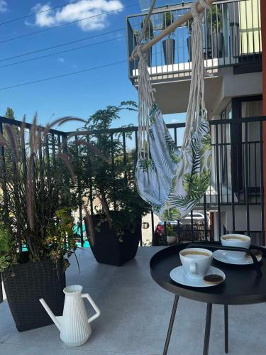 - une table avec une tasse de café sur le balcon dans l'établissement Leaf Apartament Łódź prywatne miejsce parkingowe, à Łódź