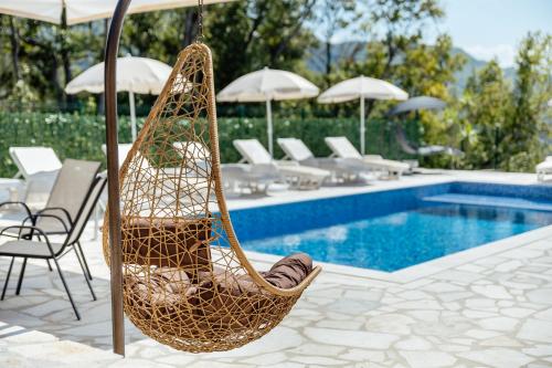a hammock by a pool with chairs and umbrellas at Villa Goranovic in Herceg-Novi