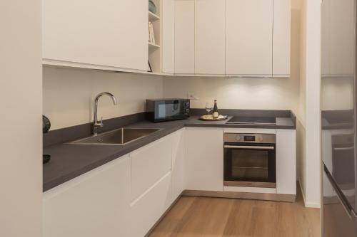 a kitchen with white cabinets and a sink and a microwave at ManaraQuattro - apartament in Como near the center with free parking - Lake Como in Como