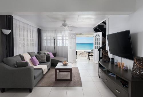 a living room with a couch and a flat screen tv at Purple Rain - Direct Seaviews, 2 Bedroom, 2 Bathroom, 3 Terrace Beachfront Bliss in Saint Peter