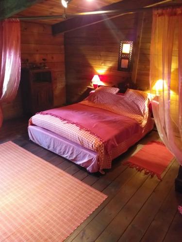 une chambre avec un lit dans une cabane en rondins dans l'établissement Gîte cadre champêtre, à Auterive