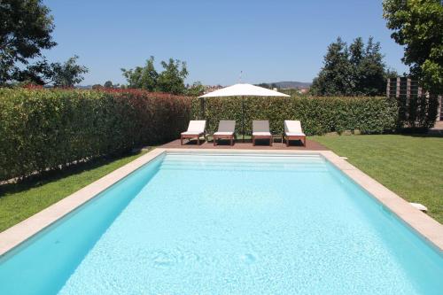 a swimming pool with two chairs and an umbrella at PORTO - Penafiel - QUINTA DE SANTIAGO COUNTRY HOUSE in Penafiel