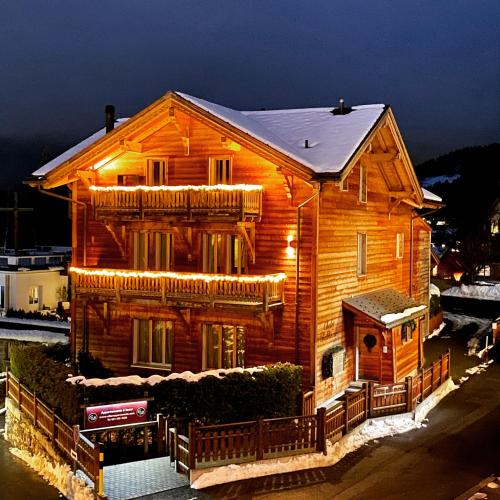 a wooden house with lights on the front of it at Chalet Balthazar 2 in Villars-sur-Ollon