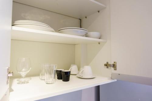 a white cabinet with dishes and glasses on a shelf at Studio Completo Consolação - Metro Higienopolis-Mackenzie in Sao Paulo