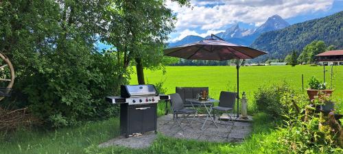 a grill with an umbrella and a table and chairs at Fewo Wald & Wiese in Bischofswiesen
